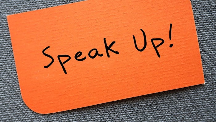 orange paper that reads "speak up!"
